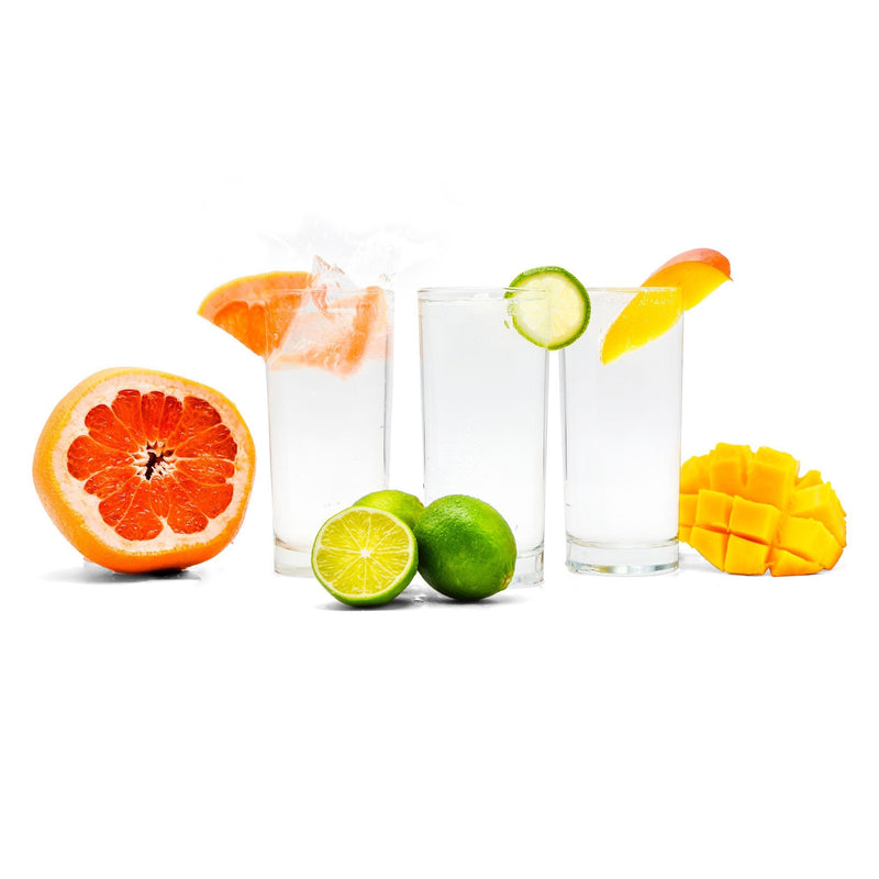 A glass of Mixed Fruit Hard Seltzer with grapefruit, lime, and mango next to it.