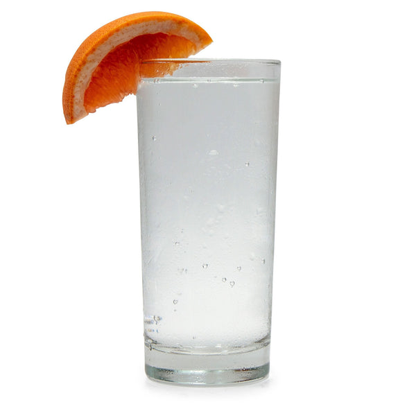 A glass of Ruby Grapefruit Hard Seltzer with a grapefruit wedge next to it.