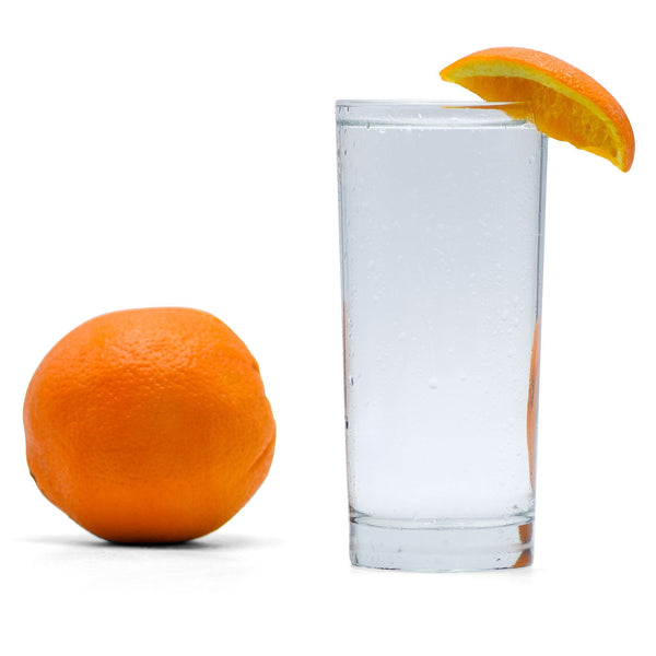 A glass of Navel Orange Hard Seltzer with an orange wedge next to it.