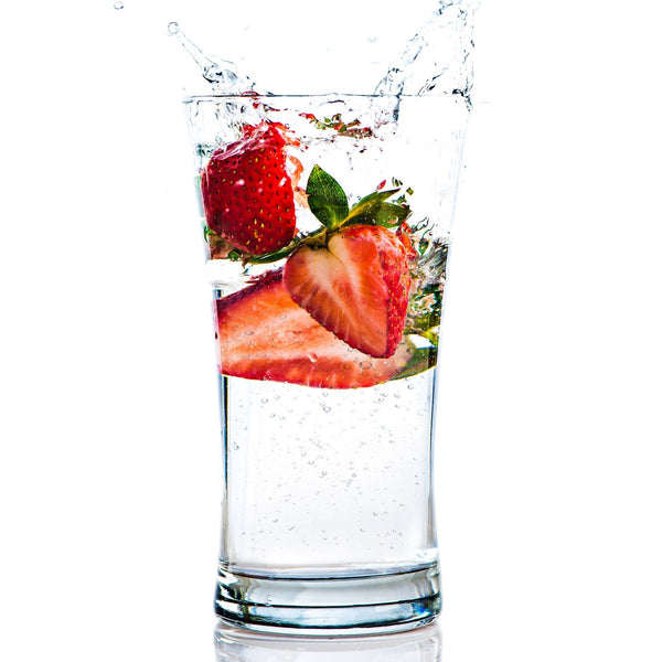 A glass of Strawberry Hard Seltzer with fresh strawberries next to it.