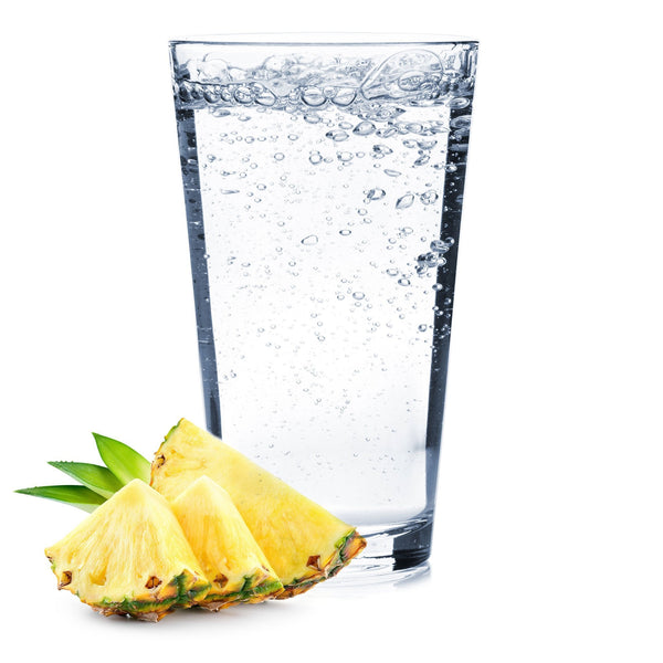 A glass of Pineapple Hard Seltzer with pineapple slices next to it.