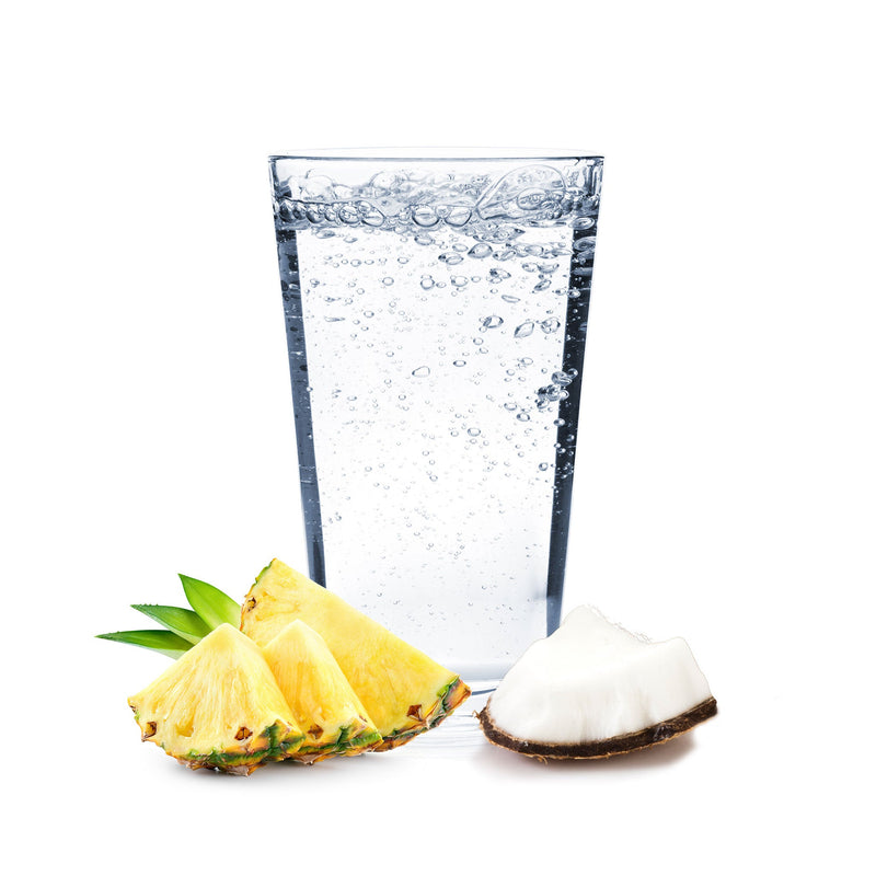 A glass of Pina Colada Hard Seltzer with pineapple and coconut pieces next to it.